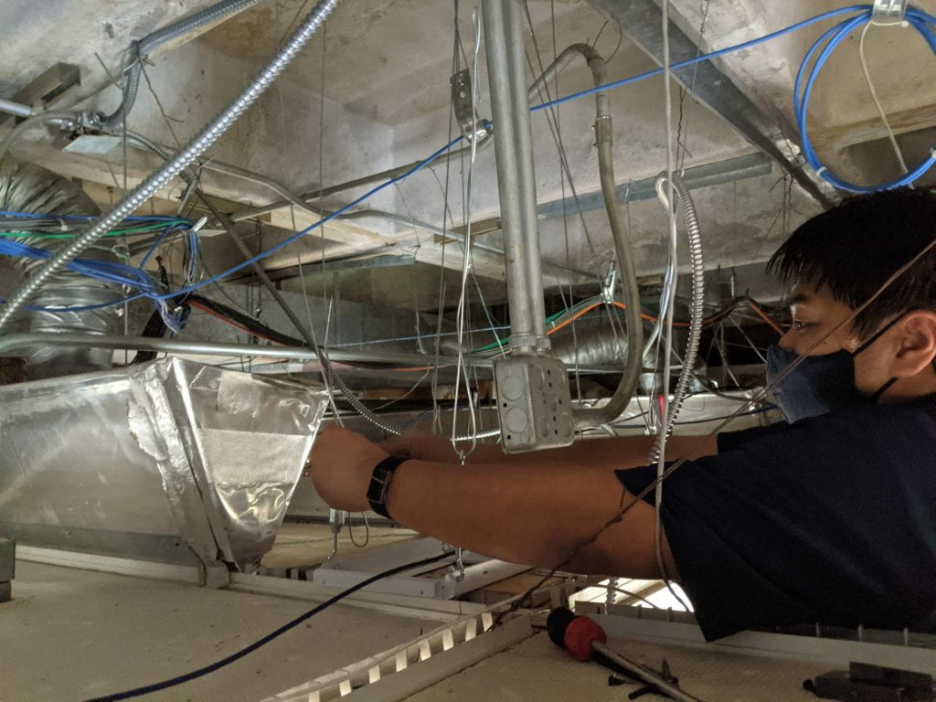 Electronics Technician installing in the ceiling